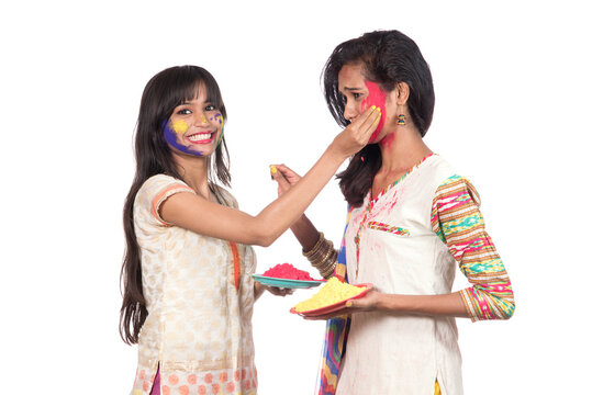 Happy young girls having fun with colorful powder at Holi festival of colors