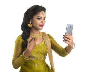 Young Indian traditional girl using a mobile phone or smartphone isolated on a white background