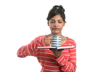 Naklejka premium Beautiful young girl with book and cup of coffee posing on a white background.