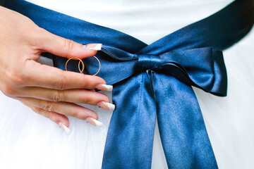 Bride Dressed in White Dress With Blue Ribbon Holding Two Wedding Rings