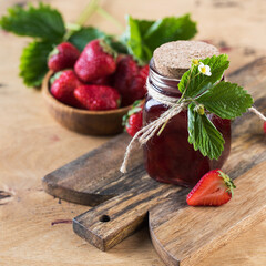 Strawberry jam in a jar on a wooden board. Fermented berries.