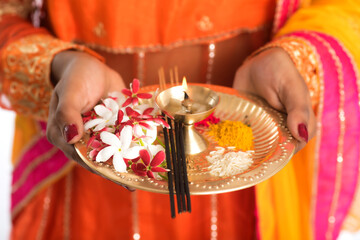 Beautiful Indian young girl holding pooja thali or performing worship on a white background
