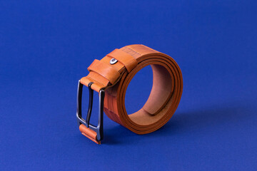 Brown reptile leather belt on blue fabric background. Fashion and shopping concept