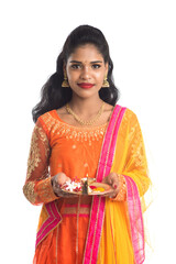 Beautiful Indian young girl holding pooja thali or performing worship on a white background