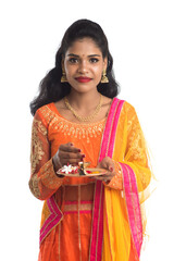 Beautiful Indian young girl holding pooja thali or performing worship on a white background