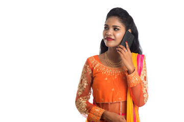 Young Indian traditional girl using a mobile phone or smartphone isolated on a white background
