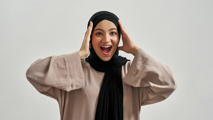 Emotional young arabian woman holding hands near head