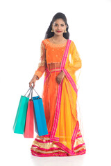 Beautiful Indian young girl holding shopping bags while wearing traditional ethnic wear. Isolated on a white background