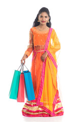 Beautiful Indian young girl holding shopping bags while wearing traditional ethnic wear. Isolated on a white background