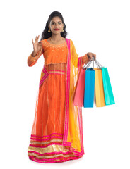 Beautiful Indian young girl holding shopping bags while wearing traditional ethnic wear. Isolated on a white background