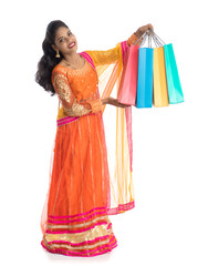Beautiful Indian young girl holding shopping bags while wearing traditional ethnic wear. Isolated on a white background