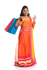 Beautiful Indian young girl holding shopping bags while wearing traditional ethnic wear. Isolated on a white background