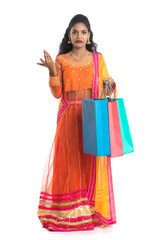 Beautiful Indian young girl holding shopping bags while wearing traditional ethnic wear. Isolated on a white background