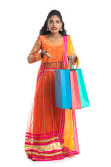 Beautiful Indian young girl holding shopping bags while wearing traditional ethnic wear. Isolated on a white background