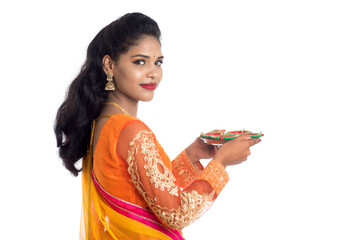 Portrait of a Indian Traditional Girl holding Diya, Girl Celebrating Diwali or Deepavali with holding oil lamp during festival of light on white background - obrazy, fototapety, plakaty