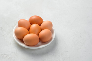 Chicken eggs on a white plate on a gray background.
