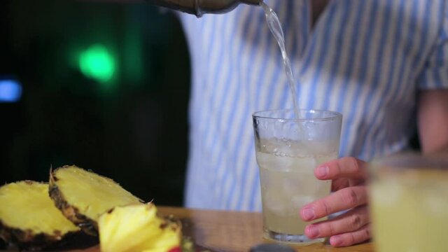 mixologists pouring a pineapple drinks into glass at house night party