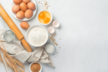 Fototapeta na wymiar Flour, eggs, sugar, rolling pin on a gray background. Ingredients for baking.
