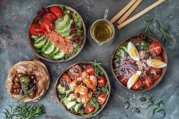 Set of Tuna , shrimp and salmon fresh salads served in coconut bowls decorated with rosemary on blue clay background