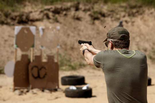 Unrecognisable man practising shooting pistol at the shooting range