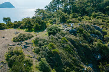 Woman traveler do sea coast hiking along rocky shore, aerial view.