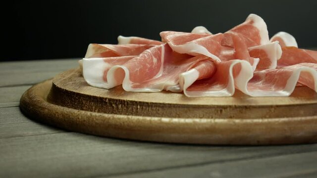 Italian prosciutto crudo, wooden plate of raw ham, cold cuts video slow motion