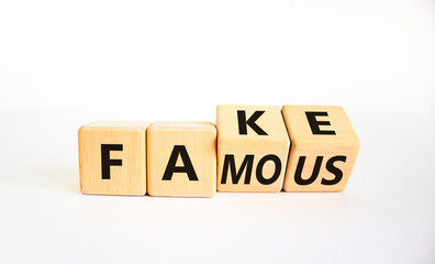 Fake famous symbol. Turned the wooden cube and changed the word fake to famous. Beautiful white background. Business and fake famous concept. Copy space.