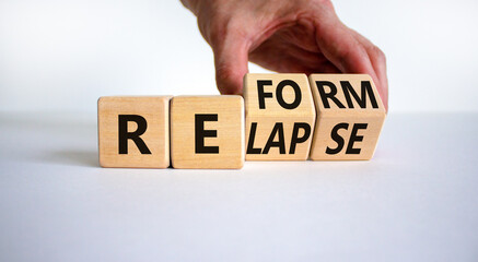Relapse or reform symbol. Businessman turns cubes and changes the word 'relapse' to 'reform'....