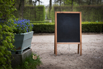 Empty sandwich chalkboard stand in a park ready to be filled