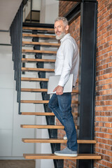 Mature tall mid-aged man standing on the stairs