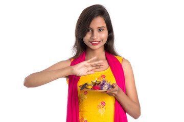 Beautiful Indian young girl holding pooja thali or performing worship on a white background