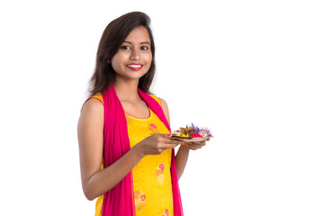 Beautiful Indian young girl holding pooja thali or performing worship on a white background