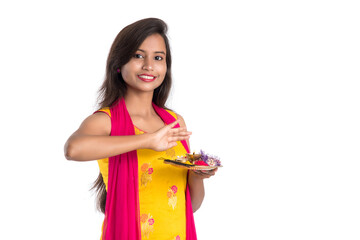 Beautiful Indian young girl holding pooja thali or performing worship on a white background