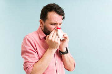 Young man blowing his nose with blood - obrazy, fototapety, plakaty