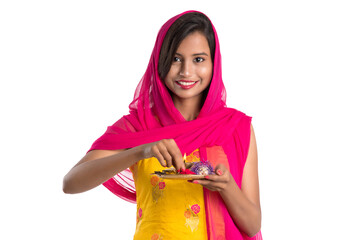 Beautiful Indian young girl holding pooja thali or performing worship on a white background