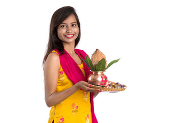 Indian girl holding a traditional copper Kalash with Pooja Thali, Indian Festival, copper Kalash with coconut and mango leaf with floral decoration, essential in Hindu Pooja.