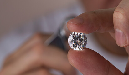 Close up of diamond dealer's hands evaluating diamond at international jewelry exhibition. High...