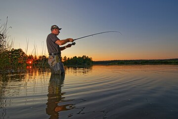 Fisherman catching the fish in the lake during summer sunset