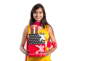 Portrait of young happy smiling Indian Girl holding gift boxes on a white background.