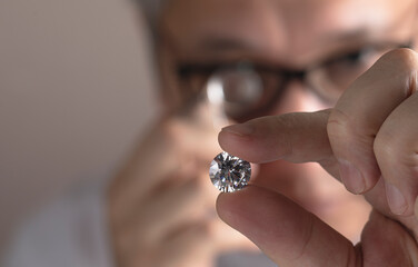 Close up of diamond dealer's hands evaluating diamond at international jewelry exhibition. High...