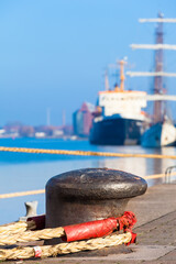 Berthing Place Detail / Harbor Bollard with thick rope and old ship background at long wharf (copy...