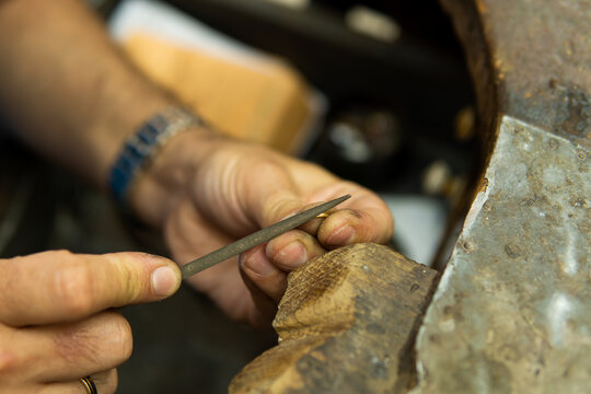Joyero trabajando en su taller puliendo un anillo de oro con una lima