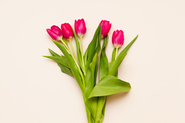 delicate bouquet of red tulips with green leaves on a pastel pink background top view. Easter minimalism concept.