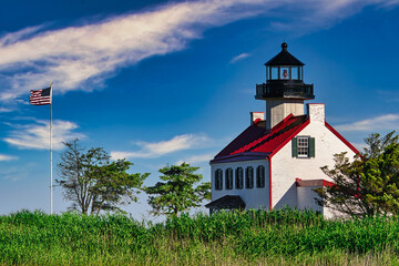 The East Point Lighthouse with a waving American Flag in Maurice River County, New Jersey. 