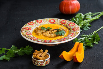 Delicious healthy pumpkin soup, herbs, and ingredients for the dish. Creative atmospheric decoration