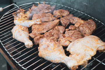 Barbecue - raw and grilled chicken legs and pork neck on the grate