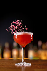 magnificent view on wine glass with red drink decorated with a sprig of flowers on bar.