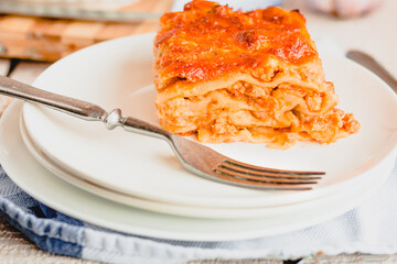 Piece of tasty hot lasagna served with on a white plate. Italian cuisine, menu, recipe. Homemade meat lasagna. Close up