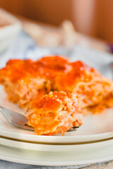 Slice of delicious beef lasagne with cheese crust on a white plate viewed close up on the side showing the layers.Restaurant menu, recipe