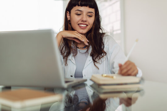 Cheerful young businesswoman making notes at home